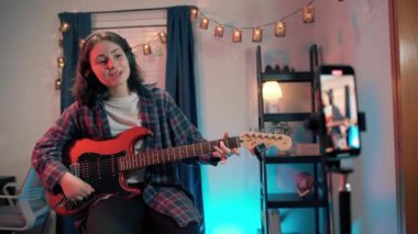 Otururken gitar çalan neşeli kadın blogcu. Yüksek kalite 4k görüntü