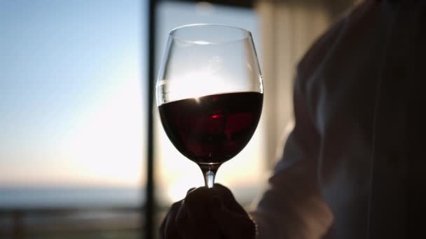 日落时 年轻人在家里的窗边喝红酒 高质量的4K镜头 — 图库视频影像