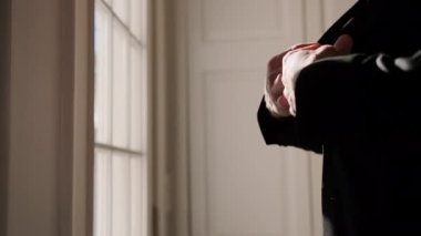 Silhouette of a man putting on his jacket in dark room on the background of the window. High quality 4k footage