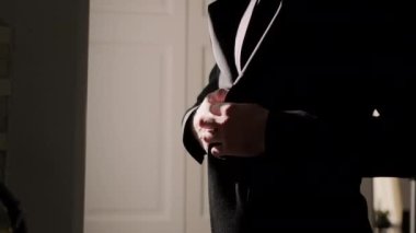 Silhouette of a man putting on his jacket in dark room on the background of the window. High quality 4k footage