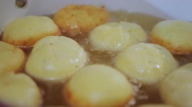 Cooking berliners or doughnuts on a frying pan. fat and oil boiling hot temperature. Close up. High quality 4k footage