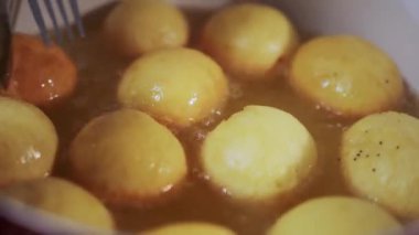 Cooking berliners or doughnuts on a frying pan. fat and oil boiling hot temperature. Close up. High quality 4k footage