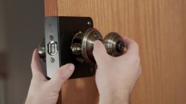 A mans hands using a screwdriver to tighten new door handles onto an aged internal door. High quality 4k footage