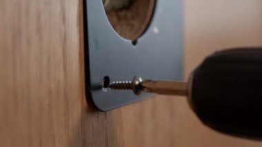 A mans hands using a screwdriver to tighten new door handles onto an aged internal door. High quality 4k footage