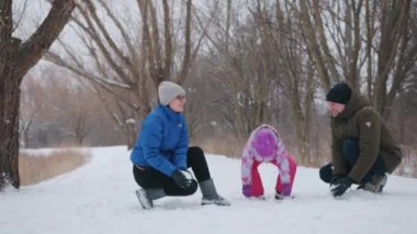 Happy family playing with snow in a park on a sunny winter day,. High quality 4k footage