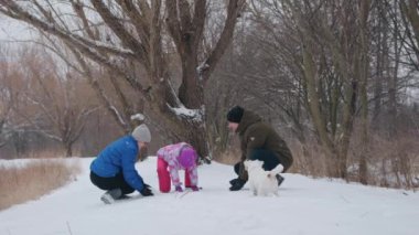 Happy family playing with snow in a park on a sunny winter day,. High quality 4k footage