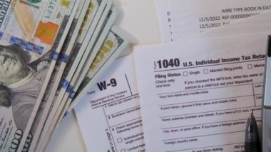 Amerikan doları vergi faturası, kalem hesap makinesi ve Amerikan parası. 1040 ve W9 bireysel vergi formları Amerikan vatandaşının masasına konur. Yüksek kalite 4k görüntü