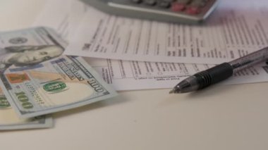 Hesap makinesi 1040 ve W9 bireysel vergi formlarının tutarı Amerikan vatandaşının masasına konur. Yüksek kalite 4k görüntü