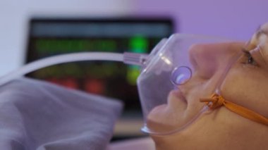Oksijen maskesi takan, klinikteki yatakta yatan olgun, beyaz bir kadının yan görüntüsü. Yüksek kalite 4k görüntü