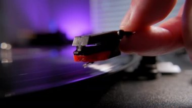 Close up shot of hands placing the vintage turntable on a spinning vinyl record. . High quality 4k footage