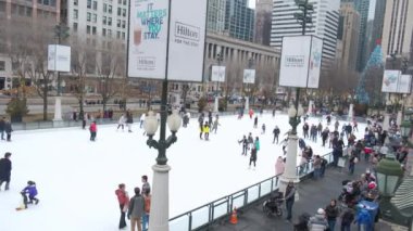 People skating on an outdoor ice rink in downtown Chicago on cloudy winter day. High quality 4k footage