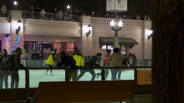 人々は曇った冬の夜にシカゴのダウンタウンの屋外アイスリンクでスケートをします 高品質4K映像 — ストック動画