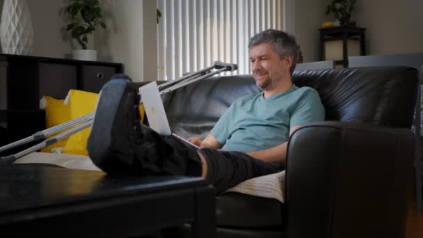 Happy Man Broken Leg Working Laptop High Quality Footage — Stockvideo