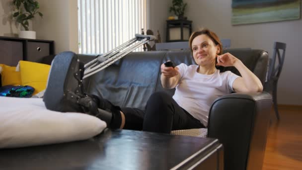 Femeie Fericită Picior Rupt Uită Televizor Lovitură Largă Imagini Înaltă — Videoclip de stoc
