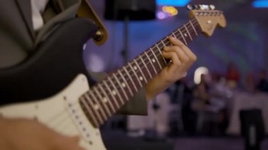 Sahnedeki bir konserde elektro gitar çalan gitariste yakın çekim. Canlı performans. Yüksek kalite 4k görüntü