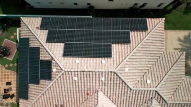 Banliyöde temiz elektrik enerjisi üretmek için çatısı güneş panelleriyle kaplı bir Amerikan yerleşim evi. Yüksek kalite 4k görüntü