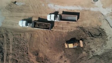 Yukarıdan aşağıya doğru geniş çekim. Bir buldozer, gelişim için bir arazi alanı oluşturur. Yüksek kalite 4k görüntü