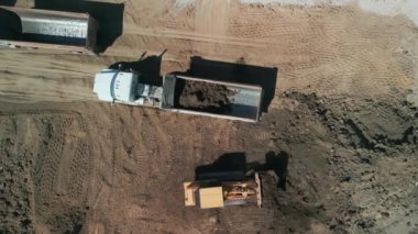 Yukarıdan aşağıya doğru geniş çekim. Bir buldozer, gelişim için bir arazi alanı oluşturur. Yüksek kalite 4k görüntü