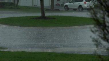 Slow Motion, heavy rain water drops falling into big puddle on asphalt, flooding the street. High quality 4k footage