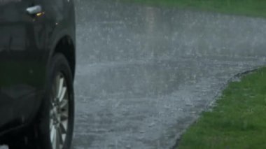 Slow Motion, heavy rain water drops falling into big puddle on asphalt, flooding the street. High quality 4k footage