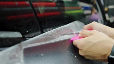 Bir arabaya koruyucu PPF filmi uygulanma süreci. Bir profesyonelin elleri laminatın koruyucu filmini uyguluyor. - Evet. Yüksek kalite 4k görüntü