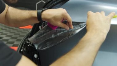 Bir arabaya koruyucu PPF filmi uygulanma süreci. Bir profesyonelin elleri laminatın koruyucu filmini uyguluyor. - Evet. Yüksek kalite 4k görüntü