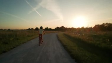 Gün batımında parkta bisiklet süren mutlu küçük kız. Yüksek kalite 4k görüntü