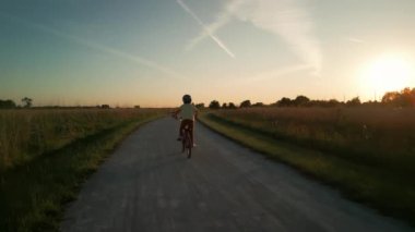Gün batımında parkta bisiklet süren mutlu küçük kız. Yüksek kalite 4k görüntü