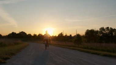 Gün batımında parkta bisiklet süren mutlu küçük kız. Yüksek kalite 4k görüntü