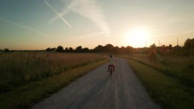 Gün batımında parkta bisiklet süren mutlu küçük kız. Yüksek kalite 4k görüntü