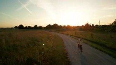Gün batımında parkta bisiklet süren mutlu küçük kız. Yüksek kalite 4k görüntü