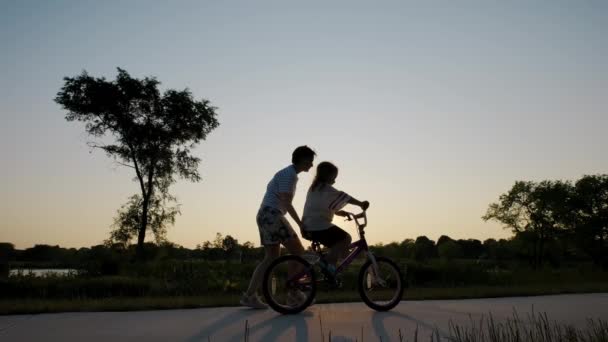 엄마는 딸에게 자전거타는 가르친다 가족의 시절의 공원에서 자전거 실루엣을 배우는 — 비디오