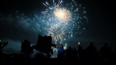 Silhouettes of group people watching fireworks in the night sky suitable for July 4th or New Years celebrations. Wide view. High quality 4k footage