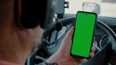 Kamyonetteki sürücü elinde yeşil ekran olan bir telefon tutuyor. Dikiz aynası yakın. Yüksek kalite 4k görüntü