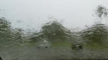 Arabanın ön camındaki silecekler yağmur damlalarını kaldırıyor. Manzarayı kapat. Yüksek kalite 4k görüntü