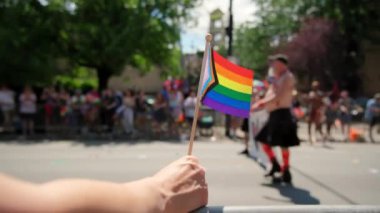 Hand hold Pride Flag ve geçit törenindeki insanların yakın çekim görüntüleri. Gündüz çekimi. - Evet. Yüksek kalite 4k görüntü