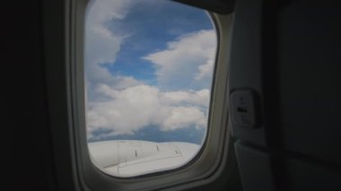 Bulutlarda uçan uçak kanadı ve mavi gökyüzü planı. Yolcu lombozunun penceresinden bak. - Evet. Yüksek kalite 4k görüntü