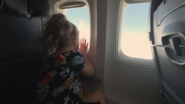 一个小女孩坐在飞机上 从飞机舷窗往外看 高质量的4K镜头 — 图库视频影像