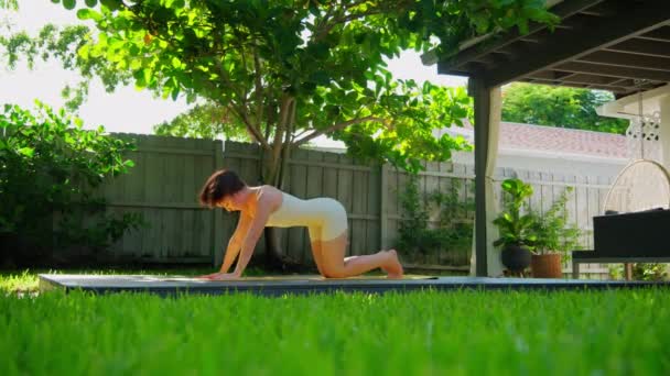穿着运动服的女人站在垫子上 在美丽的热带后院花园练习瑜伽 高质量的4K镜头 — 图库视频影像
