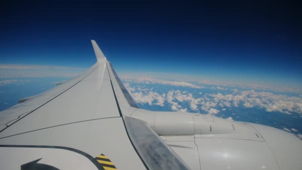 飛行機が飛行機の翼と青空を飛行する飛行機は ポートホールの窓を通して乗客に見られる ワイドショット 高品質の4K映像 — ストック動画