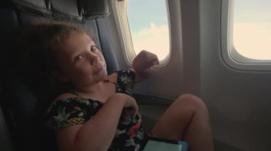 Küçük bir kız uçakta oturuyor ve oynuyor. Yüksek kalite 4k görüntü