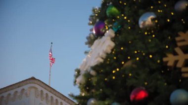 Santa Barbara, Kaliforniya 'daki bulanık Noel ağacı elementi, güneşli bir günde palmiye ağaçları ve Amerikan bayrağının arka planına karşı. Yüksek kalite 4k görüntü