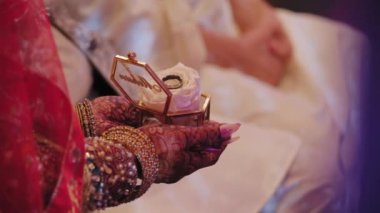 Nikah törenindeki unsurları yakından çek. Geleneksel Hint alyansı giymiş kırmızı elbiseli kadın kutuda alyans taşıyor. Yüksek kalite 4k görüntü