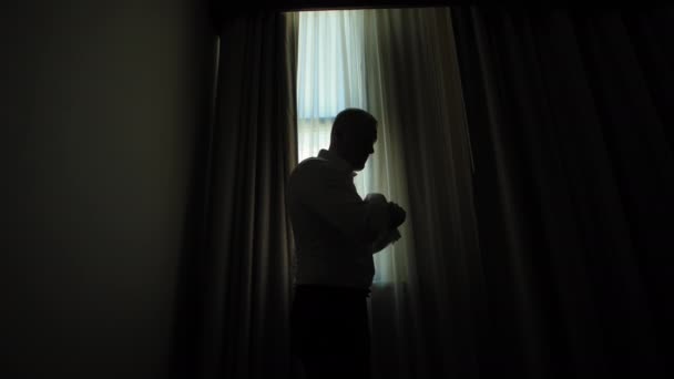 窓の背景の部屋に彼の袖口を置く男のシルエットの近くの景色 高品質の4K映像 — ストック動画