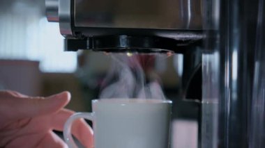 Sıcak kahvenin yavaşça makineden beyaz fincana dökülmesi. Ev ya da ofis mutfağında yeni bir kafe. Yüksek kalite 4k görüntü