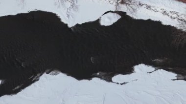 Bir kış nehrinin havadan aşağı görüntüsü, kıyılar karla kaplı. Yüksek kalite 4k görüntü