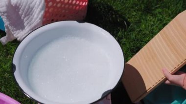Eski antika çamaşır yıkama tahtasının dışarıdaki manzarasını kapatın. Genç kadın eski bir çamaşır tahtasında yıkanıyor. Yüksek kalite 4k görüntü