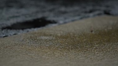 Asfalt yola yağmur damlaları ve su birikintileri düşüyor. Ağır çekim. Yüksek kalite 4k görüntü