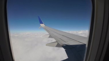 Wide view throw airplane porthole. Blue sky and big white clouds, Move camera. High quality 4k footage