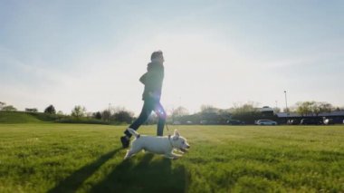 Parkta köpeği çalıştıran kadın. seyahat konsepti. Gün batımında geniş bir görüntü. Ağır çekim. Yüksek kalite 4k görüntü